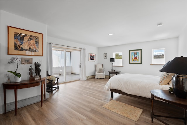 bedroom with baseboard heating and light hardwood / wood-style flooring