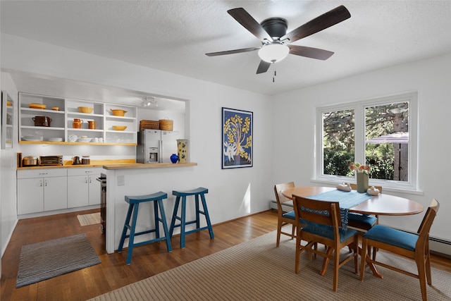 dining room with a textured ceiling, ceiling fan, and dark hardwood / wood-style flooring