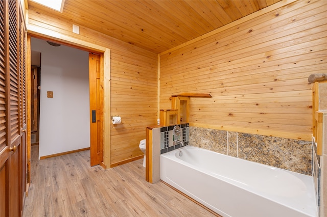 bathroom featuring wooden walls, hardwood / wood-style floors, toilet, and a tub