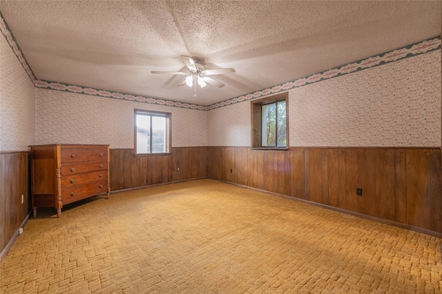 unfurnished room featuring wood walls, a textured ceiling, and ceiling fan