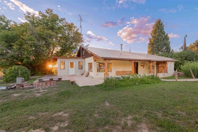 back house at dusk with a yard and a patio area