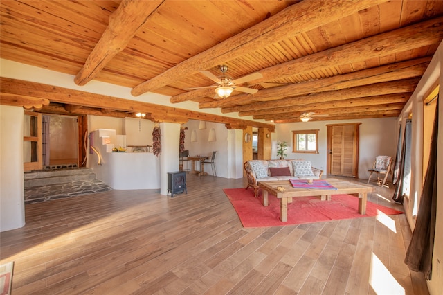 unfurnished living room with wood ceiling, hardwood / wood-style floors, beamed ceiling, and a wood stove