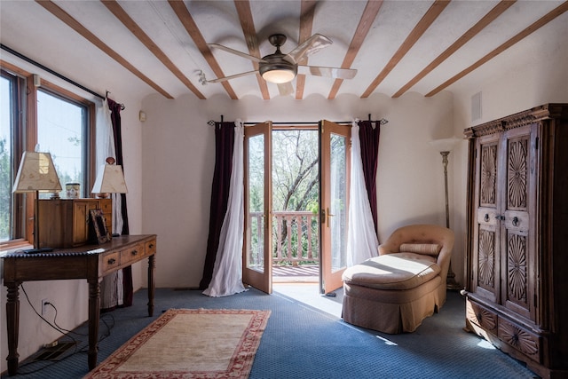 living area featuring ceiling fan, beam ceiling, carpet, and a wealth of natural light