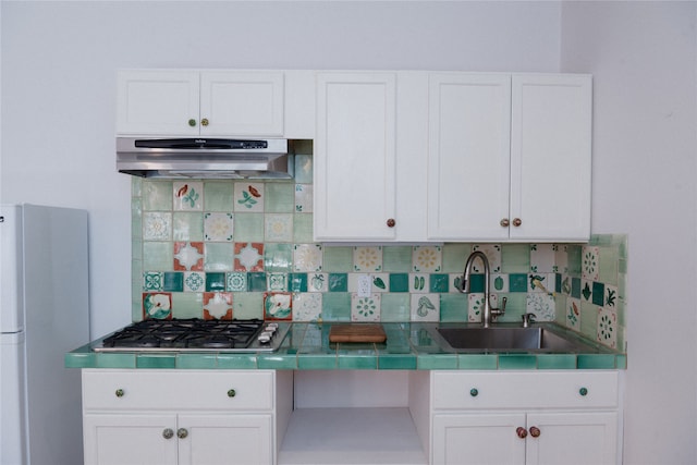 kitchen featuring refrigerator, white cabinets, and decorative backsplash