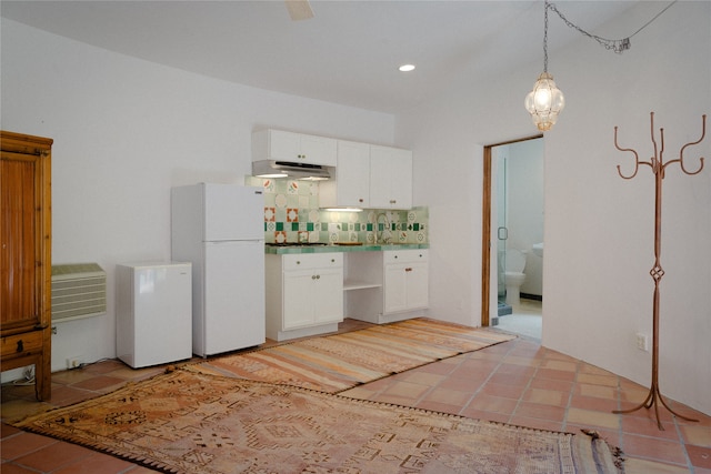 kitchen featuring pendant lighting, white refrigerator, sink, white cabinetry, and backsplash