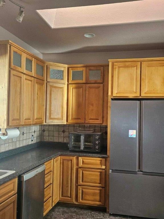 kitchen with a skylight, backsplash, and appliances with stainless steel finishes