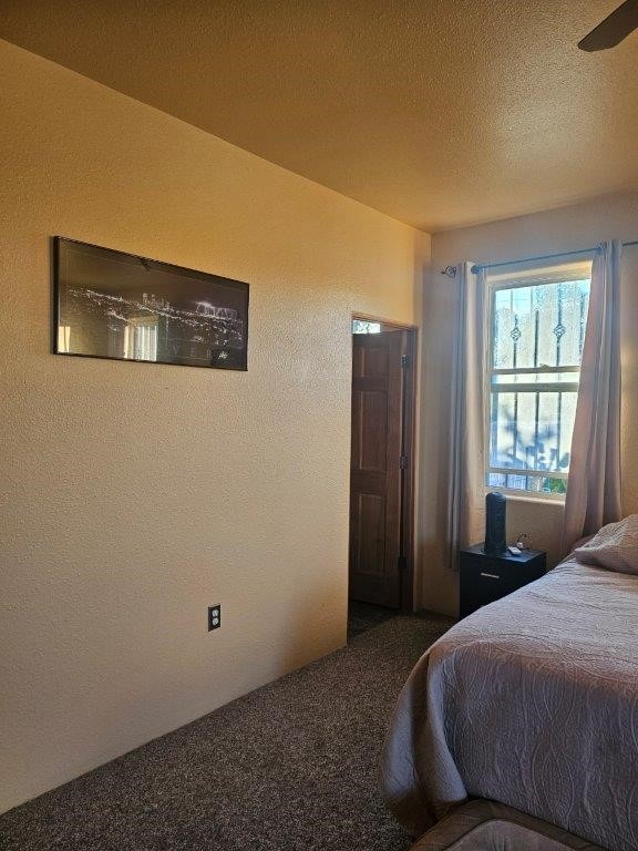 bedroom featuring a textured ceiling, carpet flooring, and ceiling fan