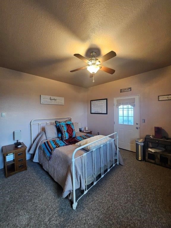 bedroom with ceiling fan, a textured ceiling, and dark colored carpet