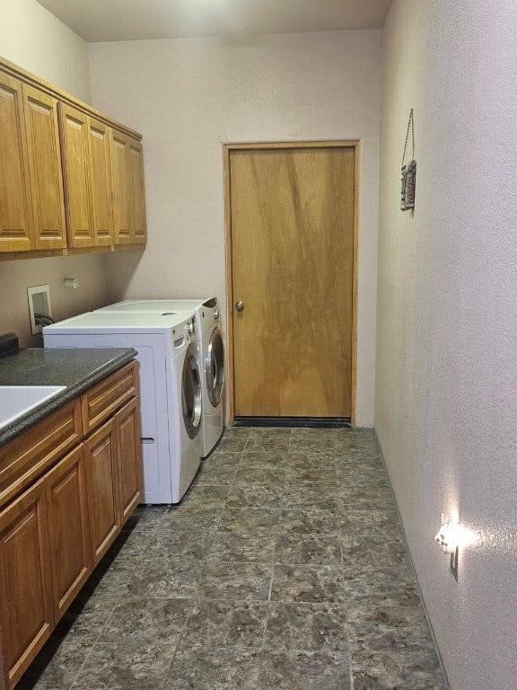 washroom featuring washing machine and dryer, cabinets, and sink