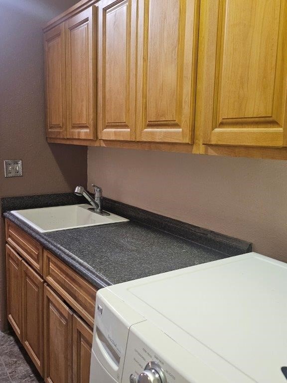 clothes washing area featuring cabinets, washer / dryer, and sink