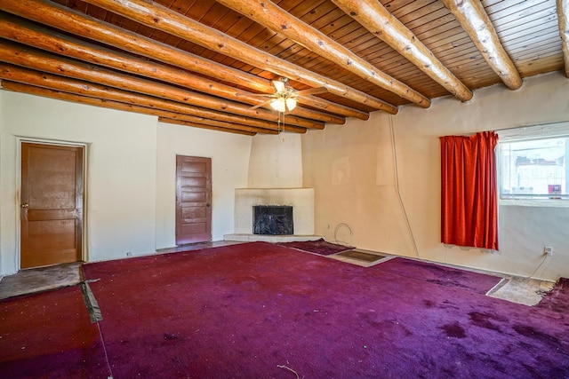 unfurnished living room featuring ceiling fan, a fireplace, beam ceiling, and wood ceiling