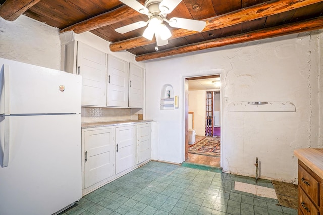 kitchen with beamed ceiling, ceiling fan, wooden ceiling, white fridge, and white cabinetry