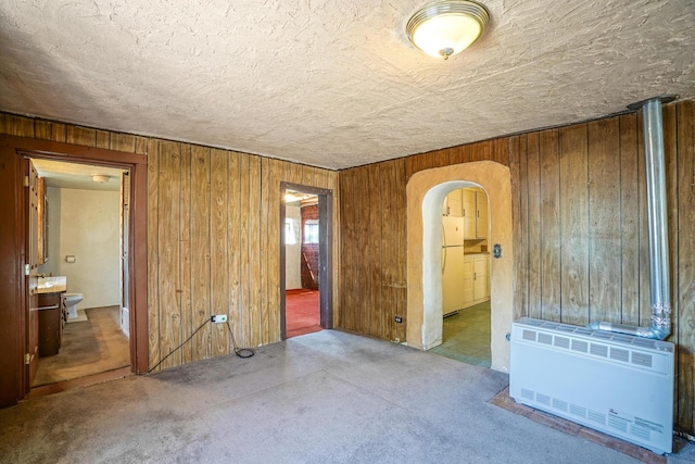 unfurnished room featuring heating unit, carpet, and wooden walls