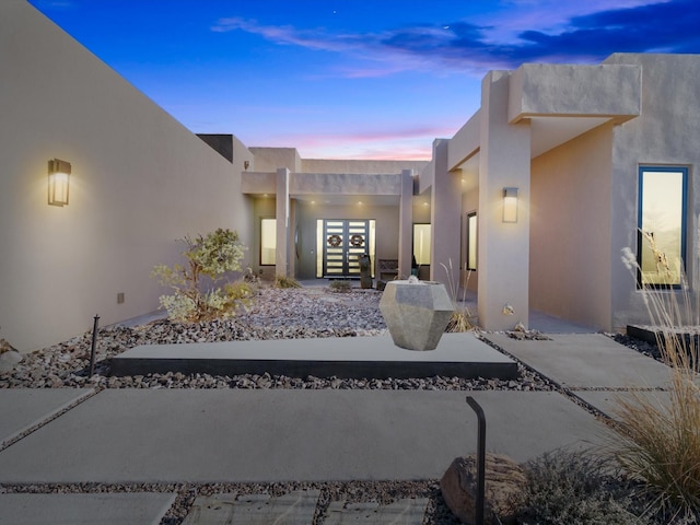 exterior entry at dusk featuring french doors and a patio