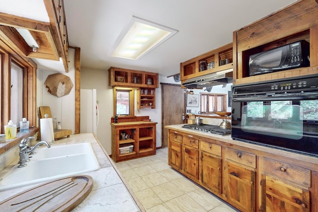 kitchen featuring light tile patterned flooring, a healthy amount of sunlight, sink, tile countertops, and black appliances