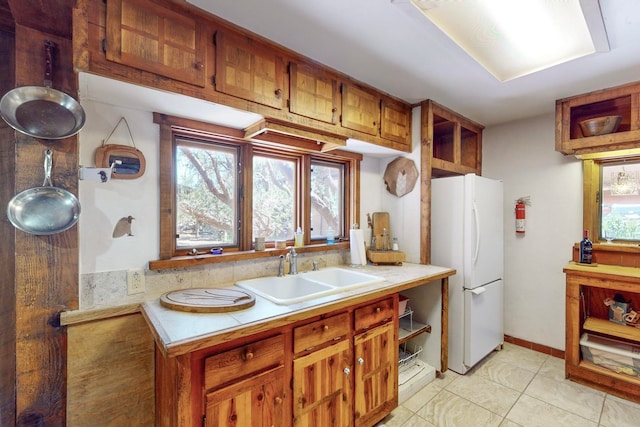 kitchen with white refrigerator, sink, and light tile patterned floors