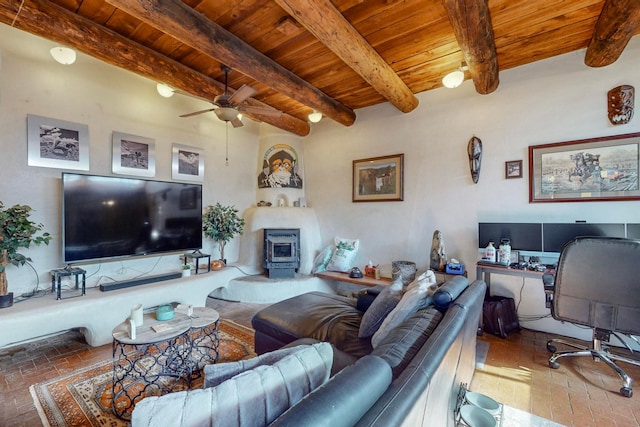 living room with ceiling fan, beamed ceiling, a wood stove, and wooden ceiling