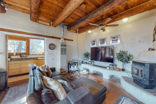 living room with ceiling fan, wooden ceiling, beam ceiling, and a wood stove