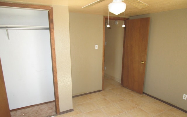 unfurnished bedroom featuring ceiling fan, a closet, and light tile patterned floors