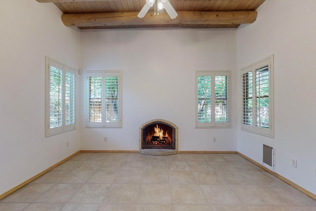 unfurnished living room with ceiling fan, beamed ceiling, light tile patterned flooring, and wooden ceiling