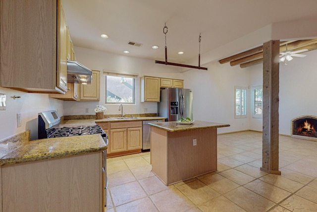 kitchen with beamed ceiling, light stone countertops, a center island, stainless steel appliances, and light brown cabinetry