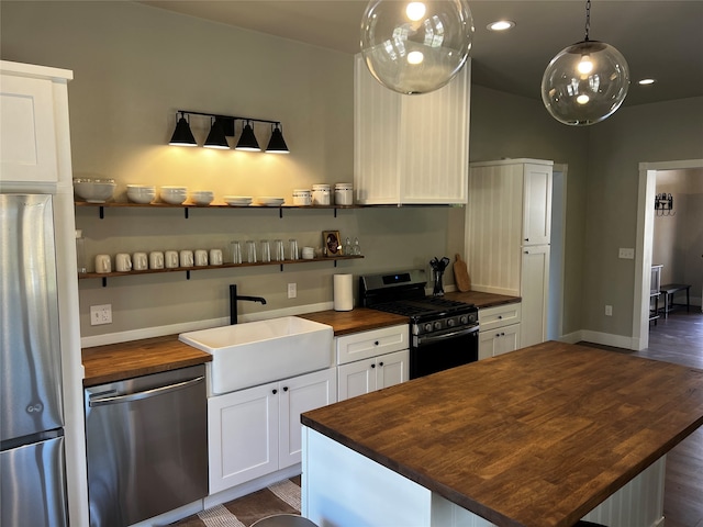 kitchen featuring white cabinets, a kitchen island, butcher block countertops, appliances with stainless steel finishes, and dark hardwood / wood-style floors