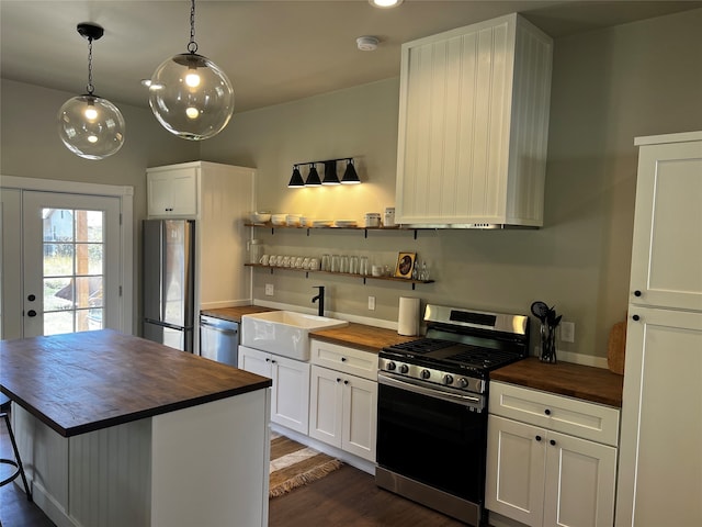 kitchen with butcher block countertops, stainless steel appliances, and white cabinets