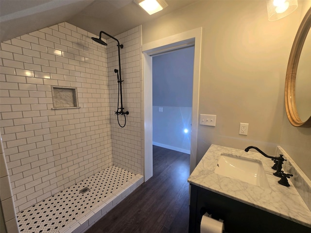 bathroom featuring vanity, hardwood / wood-style flooring, lofted ceiling, and a tile shower