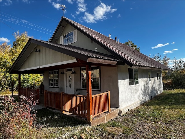 view of side of property featuring a porch and a lawn