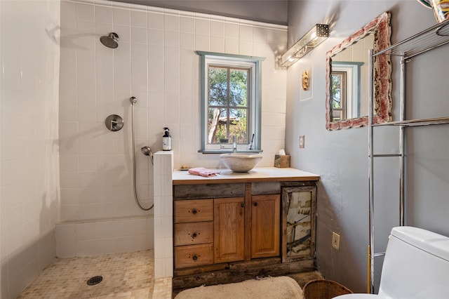 bathroom featuring a tile shower, vanity, and toilet