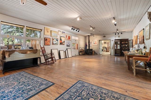 misc room with a wood stove, rail lighting, wooden ceiling, and wood-type flooring