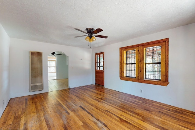 spare room featuring ceiling fan, a wealth of natural light, hardwood / wood-style floors, and a textured ceiling