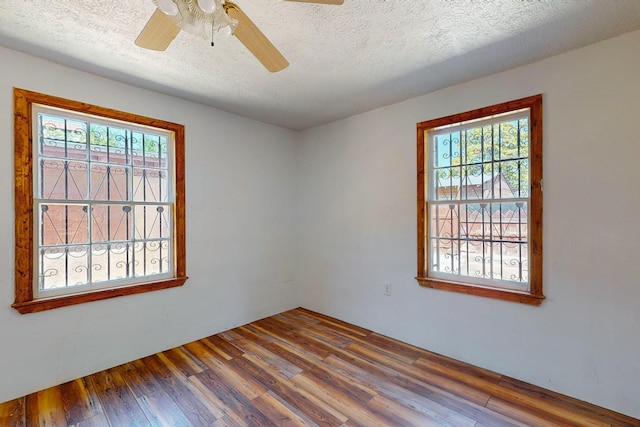 empty room featuring wood-type flooring, a textured ceiling, and a healthy amount of sunlight