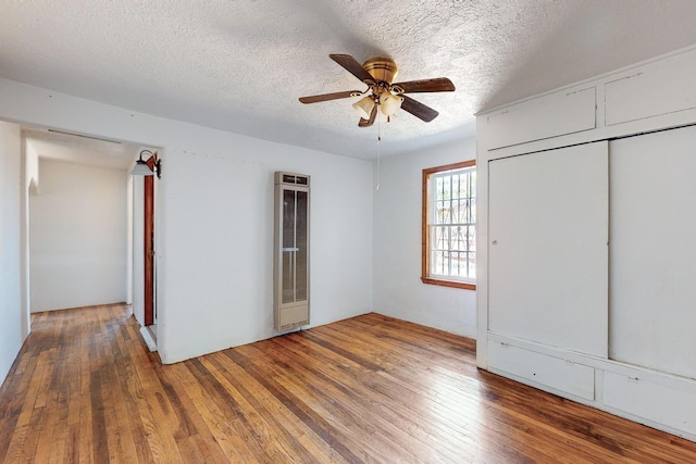 unfurnished bedroom with wood-type flooring, a textured ceiling, and ceiling fan