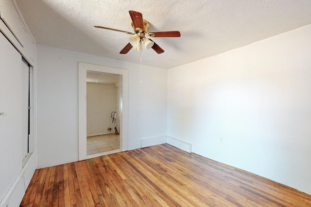 unfurnished bedroom featuring light wood-type flooring, ceiling fan, a closet, and a textured ceiling