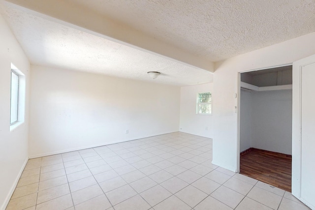 unfurnished bedroom featuring a textured ceiling, a closet, and light tile patterned floors