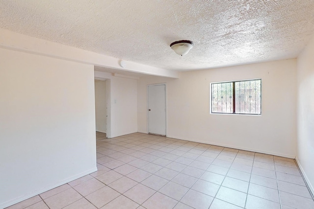 tiled spare room featuring a textured ceiling