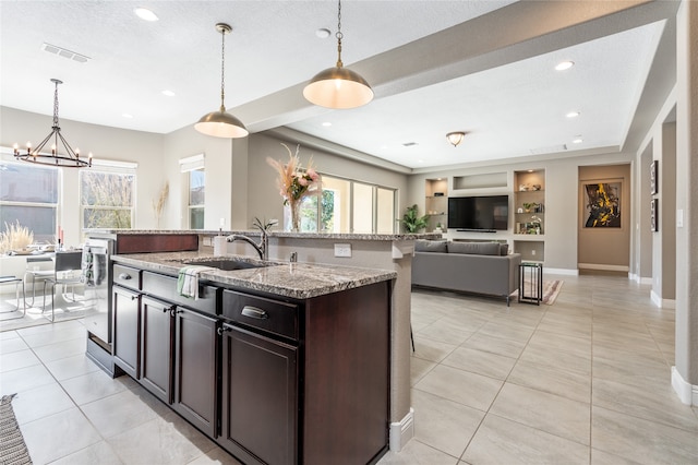 kitchen with built in features, an island with sink, sink, and a wealth of natural light