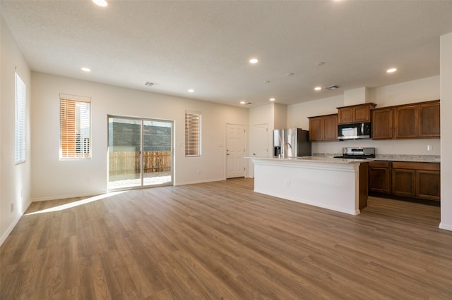 kitchen featuring a kitchen island with sink, appliances with stainless steel finishes, and hardwood / wood-style flooring