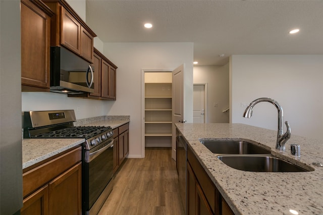 kitchen featuring light stone countertops, appliances with stainless steel finishes, sink, and light hardwood / wood-style flooring