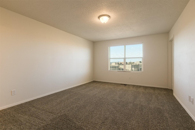 spare room with a textured ceiling and dark colored carpet