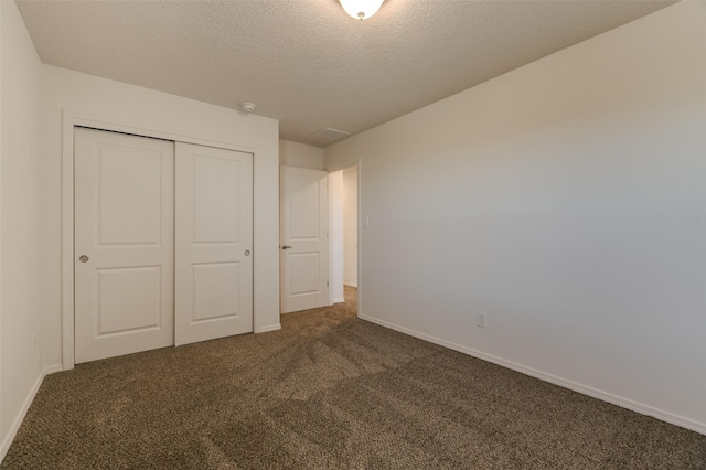 unfurnished bedroom featuring dark carpet, a closet, and a textured ceiling