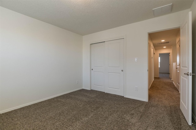 unfurnished bedroom with a closet, dark carpet, and a textured ceiling