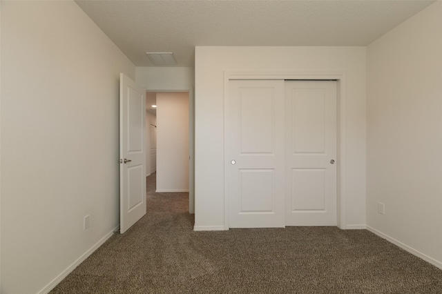 unfurnished bedroom with a closet and dark colored carpet