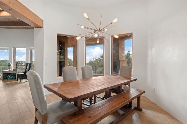 dining area featuring a chandelier, a wealth of natural light, beamed ceiling, and light hardwood / wood-style floors