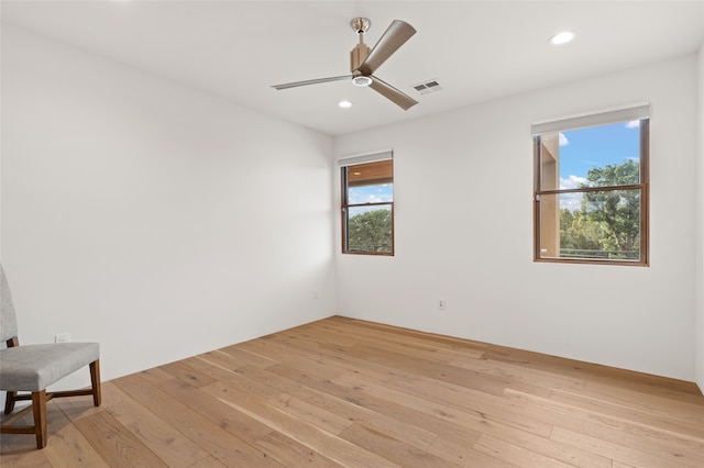 empty room featuring ceiling fan, plenty of natural light, and light wood-type flooring