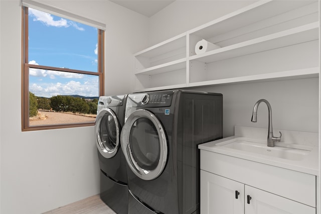 laundry room featuring cabinets, washing machine and dryer, sink, and light hardwood / wood-style flooring