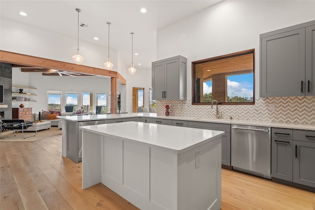 kitchen with gray cabinets, light hardwood / wood-style floors, stainless steel dishwasher, and a kitchen island