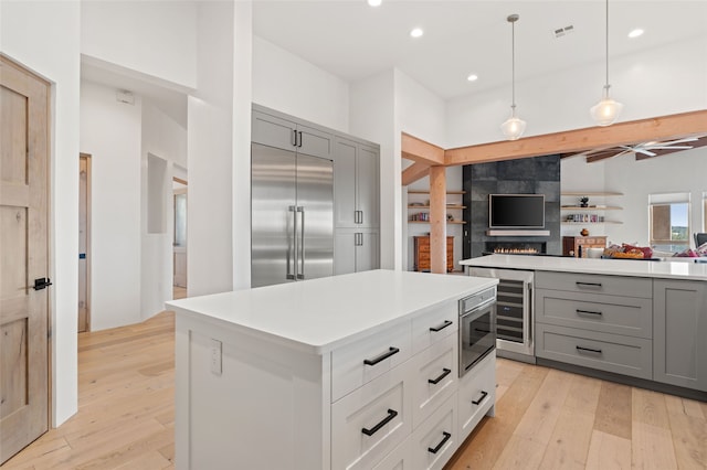 kitchen featuring pendant lighting, stainless steel appliances, gray cabinets, and light hardwood / wood-style floors