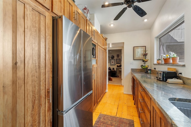 kitchen featuring light hardwood / wood-style flooring, stainless steel appliances, sink, stone counters, and ceiling fan